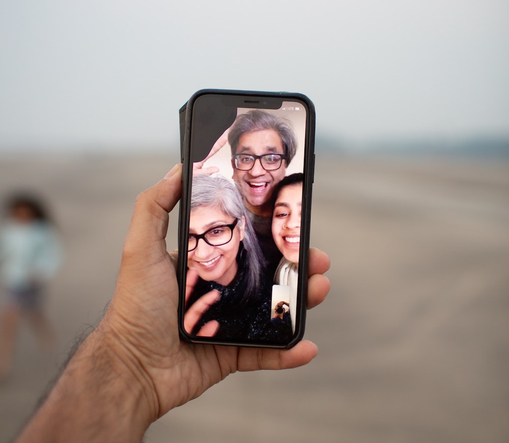 A selfie of three smiling friends on the beach
