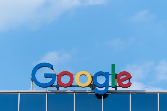 A "Google" sign on top of a building in front of a blue sky